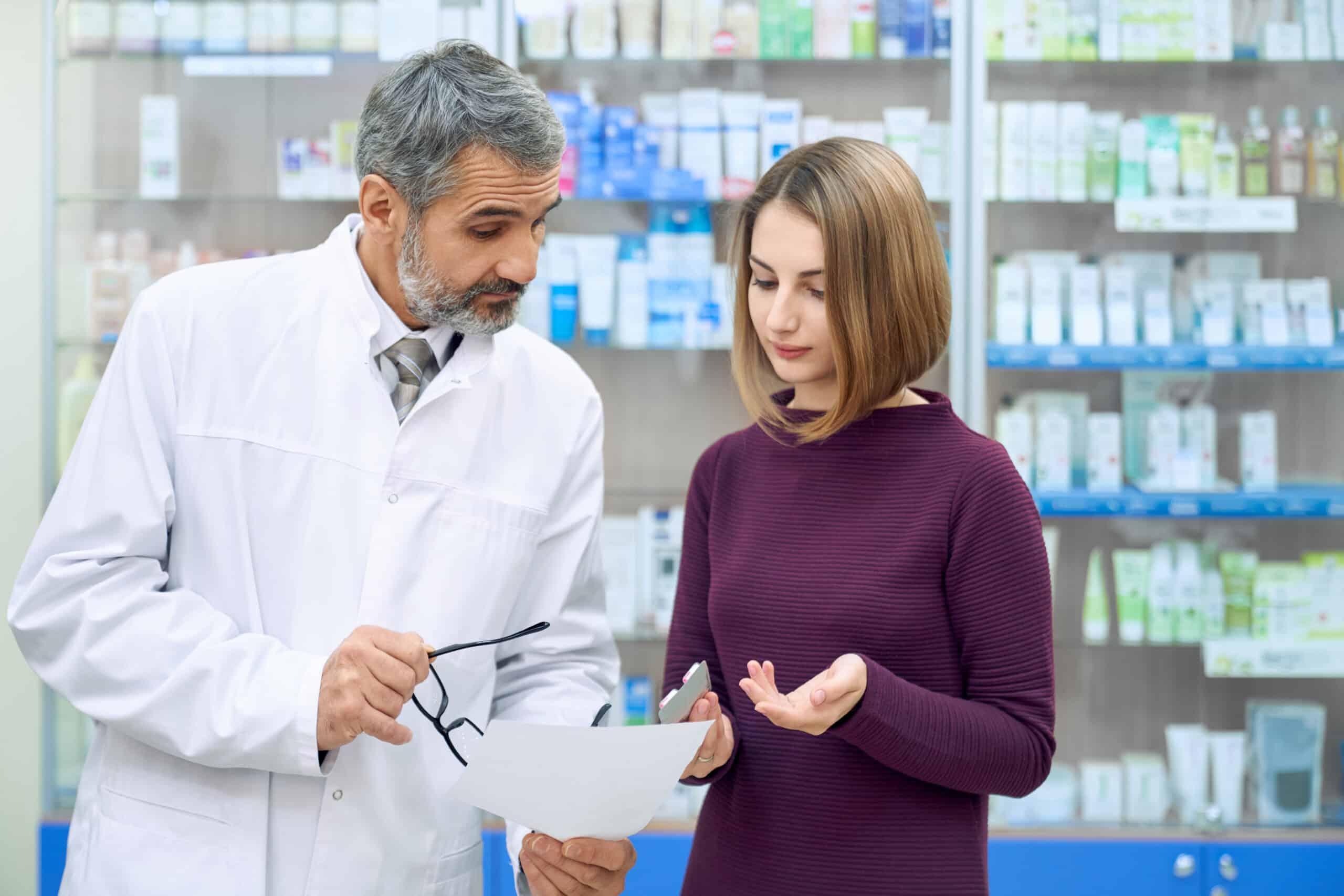 Chemist explaining prescription to woman in drugstore Chemist explaining prescription to woman in drugstore