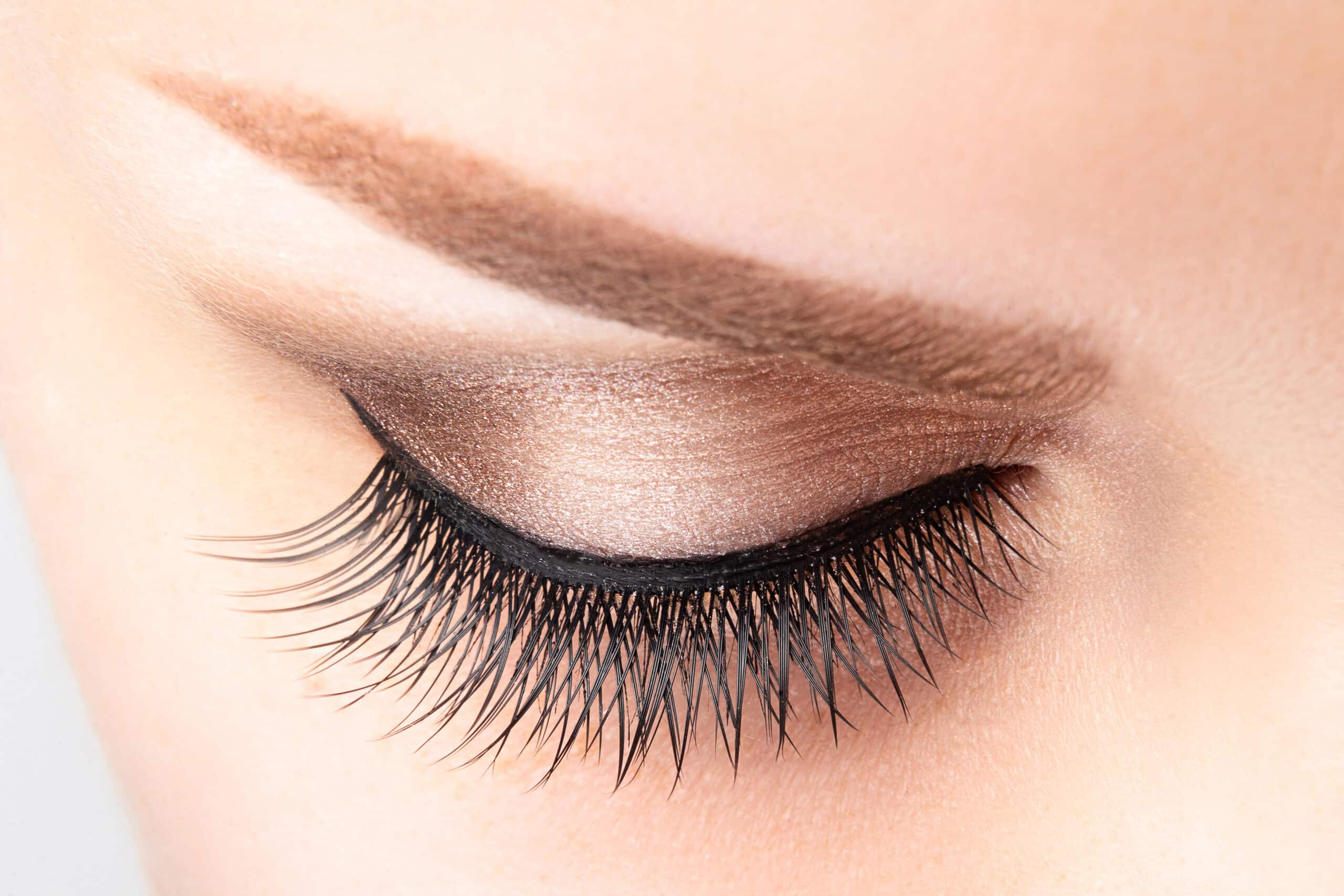 Female eye with long false eyelashes beautiful makeup and light brown eyebrow close up
