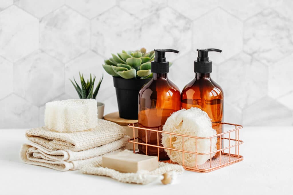 Soap and shampoo bottles and cotton towels with green plant on white table inside a bathroom background